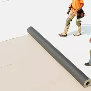 Roofers rolling out TPO membrane on flat roof
